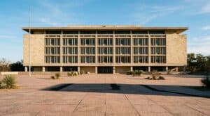 Texas state agency building facade in flat late afternoon light, representing a nursing license suspended in Texas and the board process behind it